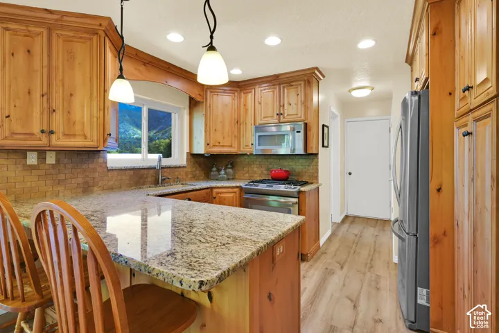 Kitchen featuring light wood cabinetry, stone countertops, a tile backsplash, stainless steel appliances, and recessed lighting