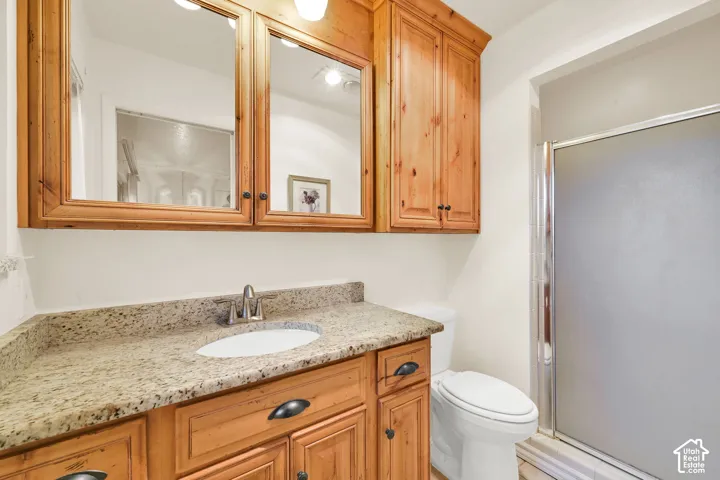Primary 3/4 bath. Vanity with wood-finish cabinetry, light-toned countertop, and undermount sink