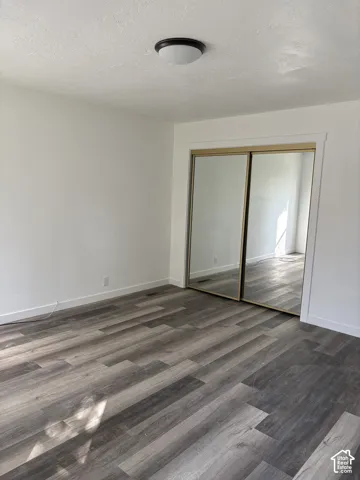 Wood-finish flooring, white walls, and mirrored closet doors