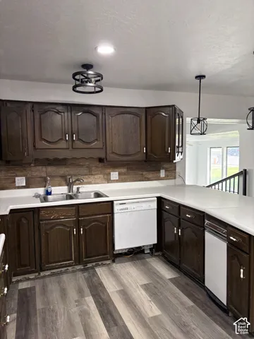Dark wood-finish cabinetry, light countertops, wood-finish flooring, and a double basin sink