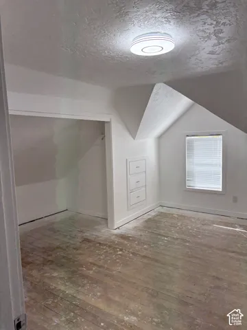 Wood-finish flooring, built-in recessed drawers, window with blinds, and flush mount lighting fixture