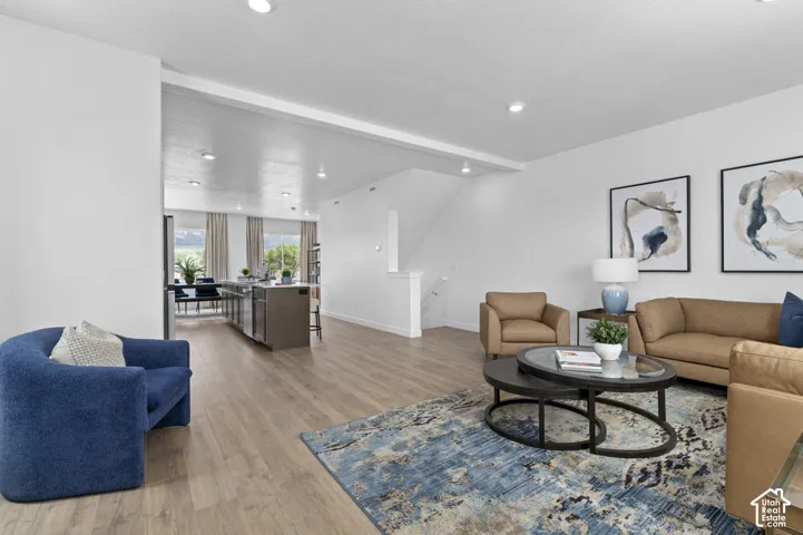 Recessed lighting illuminates the open-concept living space with wood-finish flooring