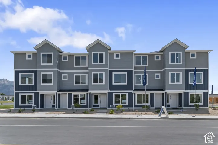 Modern townhome exterior featuring multi-toned siding, white trim, multiple windows, and a paved walkway