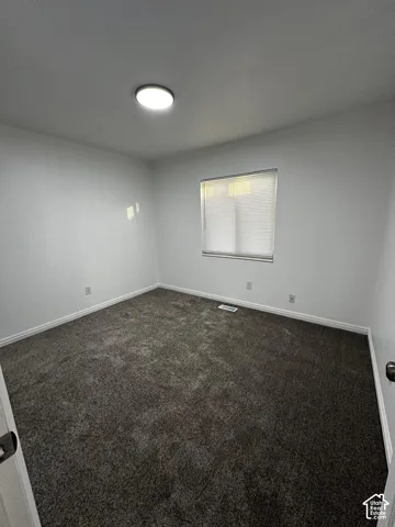 Neutral interior featuring dark carpeting, white wall finishes, and a flush-mount overhead light fixture