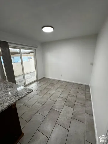 Neutral-toned tile flooring, granite-topped peninsula, and glass sliding door featuring patio access