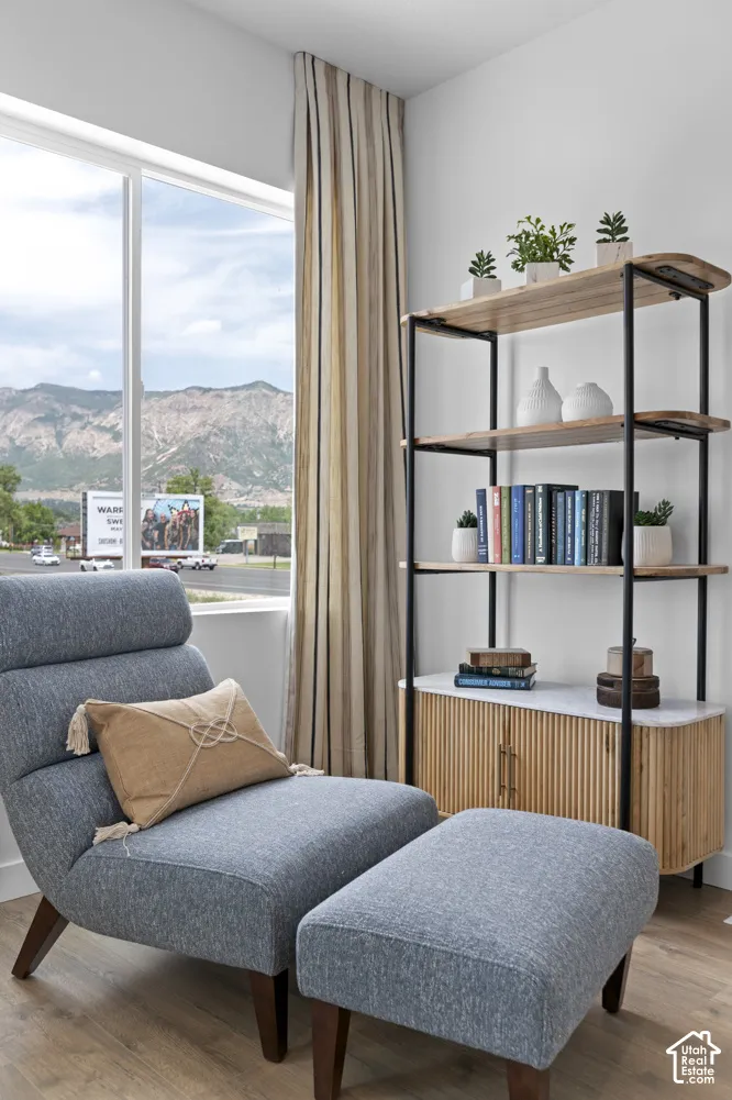 Large window, wood-finish flooring, full-height drapery, wall-mounted shelving unit, lower storage cabinet