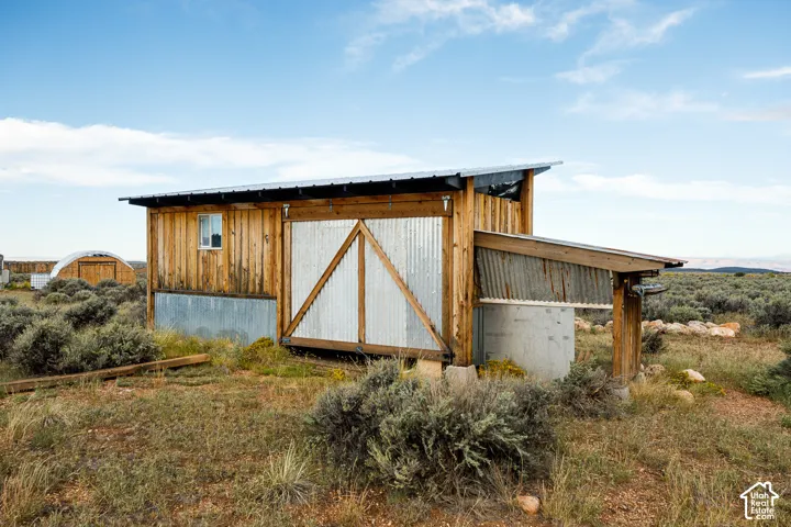 Wood-clad outbuilding with corrugated metal siding, a single pane window, and an attached lean-to structure