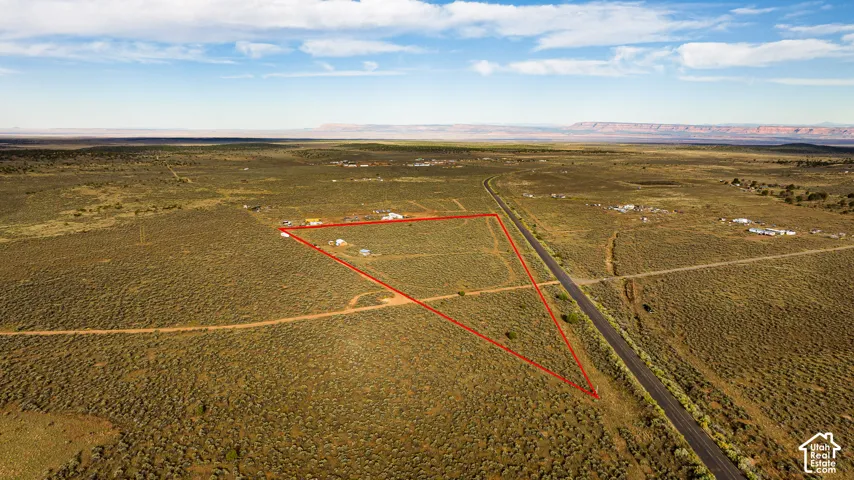 Expansive open land featuring a clear property boundary, direct road frontage, and a rural setting with distant mountains