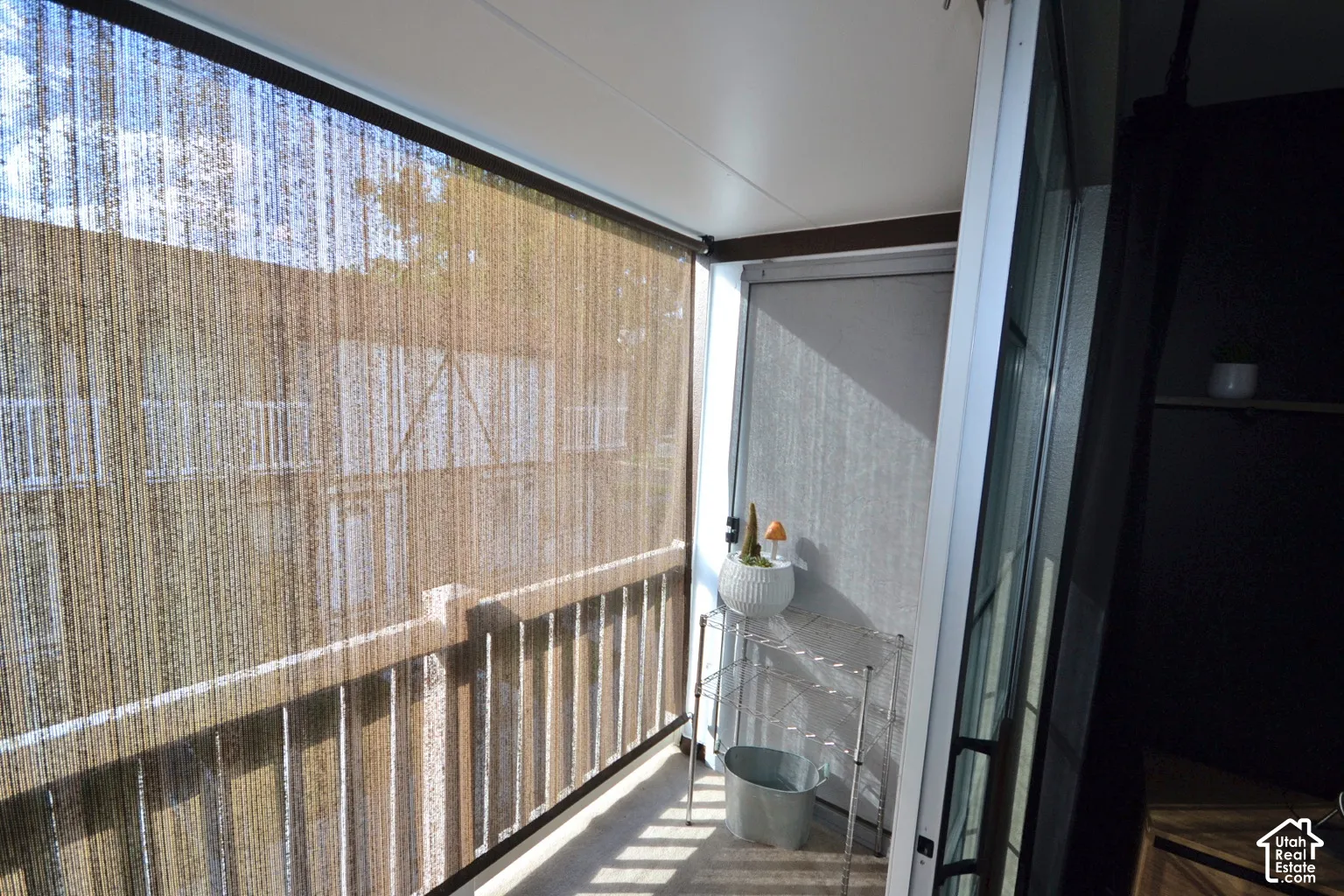 Balcony featuring a retractable roller shade, concrete flooring, and a railing
