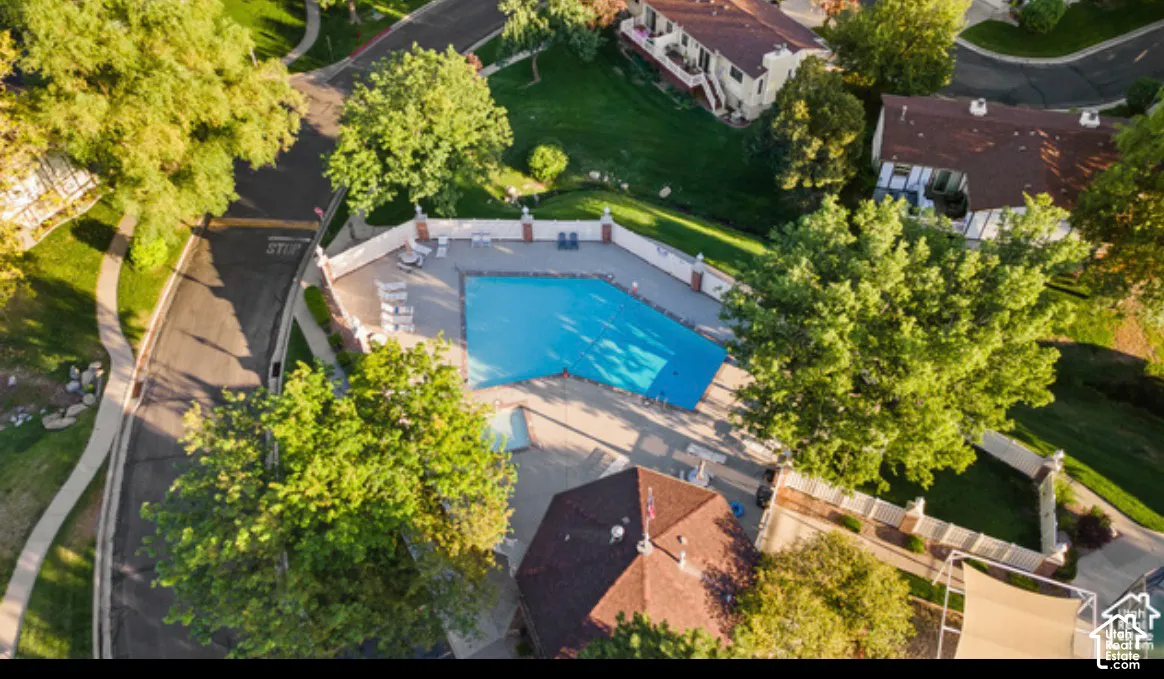 Community swimming pool featuring a concrete deck, masonry perimeter wall with brick-capped pillars, and an integrated gazebo structure