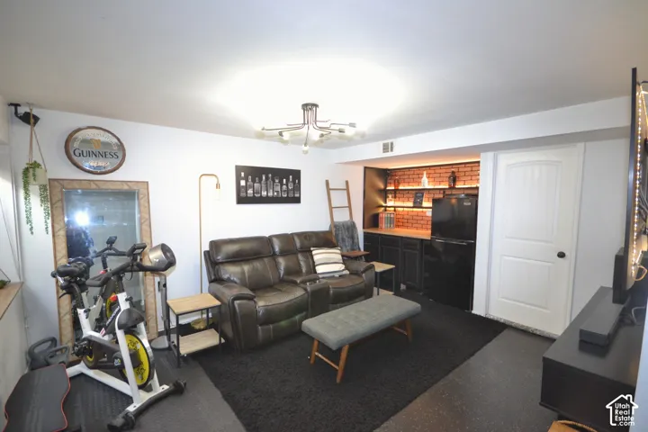 Built-in bar area featuring brick-finish accent wall, under-shelf lighting, and dark cabinetry