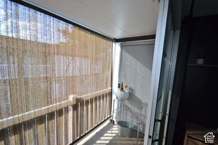 Balcony featuring a retractable roller shade, concrete flooring, and a railing
