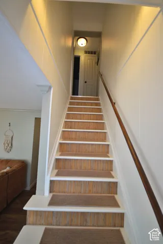 Staircase with wood-finish risers, white treads, and a wood handrail