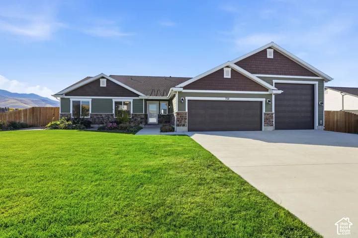 Ranch-style exterior with stone and siding accents, featuring a two-car and a one-car garage, a concrete driveway, and an expansive front lawn