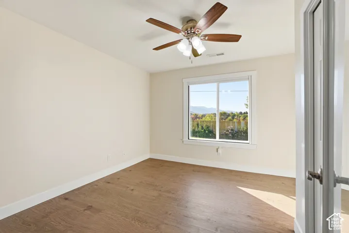 Recessed window with white trim, wood-finish flooring, ceiling fan with integrated lighting, white interior door with glass panels and brushed metal hardware, and light-colored wall paint