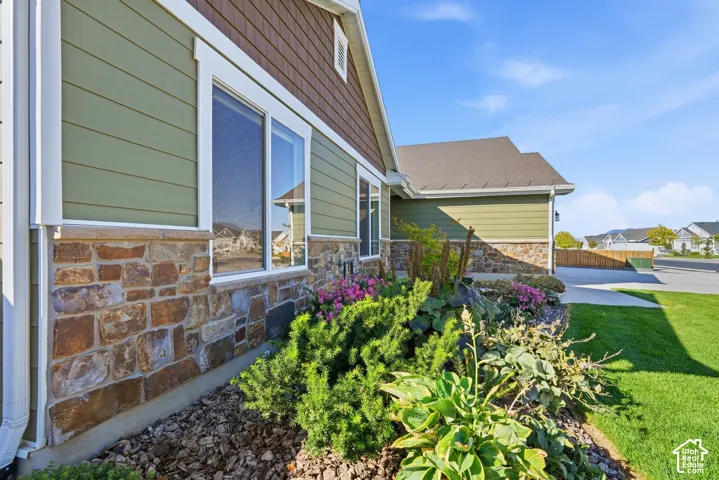 Exterior siding featuring horizontal panels and shake accents, stone veneer foundation, white-trimmed windows, and a landscaped planting bed with established greenery