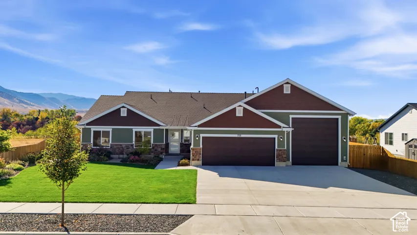 Crafted exterior featuring a two-car garage, stone accents, and a landscaped front yard with a concrete driveway