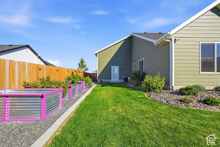 Expansive lawn area with raised garden beds, a privacy fence, and a gravel-mulched planting bed