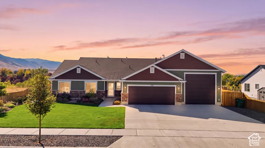 Ranch-style exterior with stone and siding facade, attached two-car garage, established front landscaping, and concrete driveway
