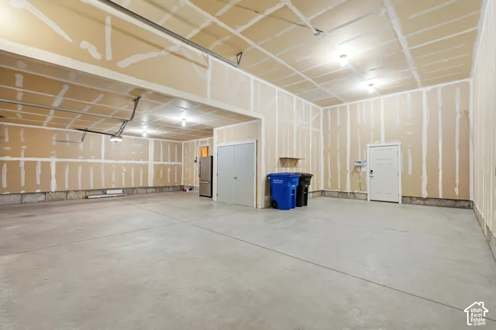 Spacious garage with exposed drywall, concrete flooring, and multiple ceiling-mounted light fixtures