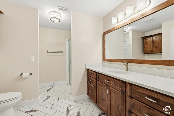 Vanity with wood cabinetry, light-toned countertop, and undermount sink