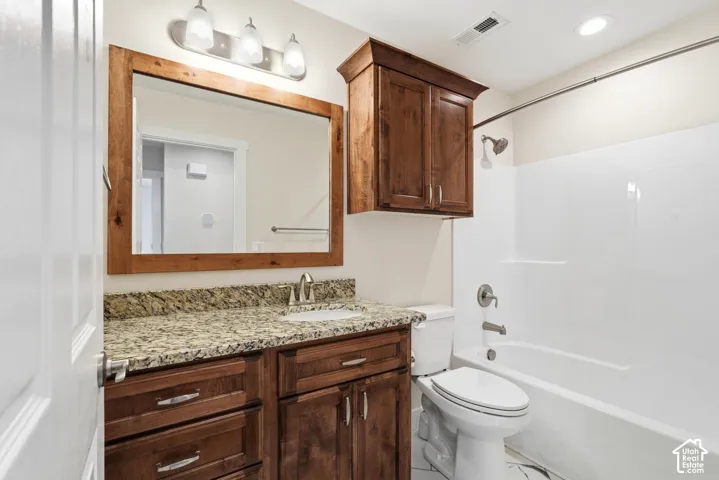 Vanity with a granite countertop, undermount sink, and wood-finish cabinetry