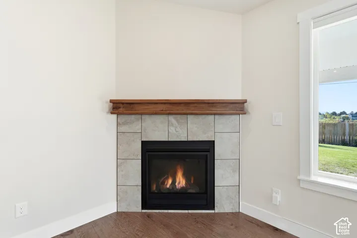 Corner fireplace with a tile surround, wood mantel, and a large window