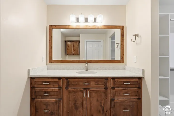 Wood-finish vanity with an integrated sink, light-toned countertop, framed mirror, and overhead lighting