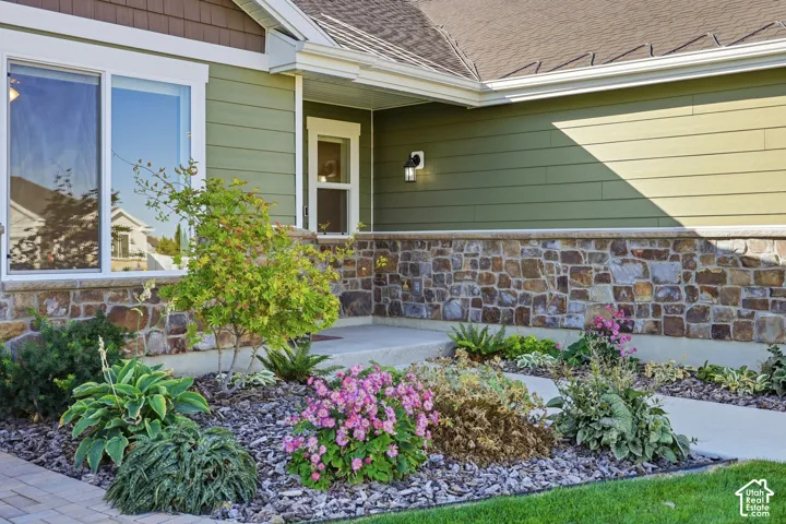 Stone facade with green siding, white-trimmed windows, and a covered entry