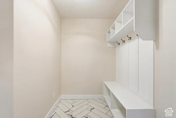 Built-in white storage unit with cubbies and hooks, integrated bench seating, and patterned tile flooring