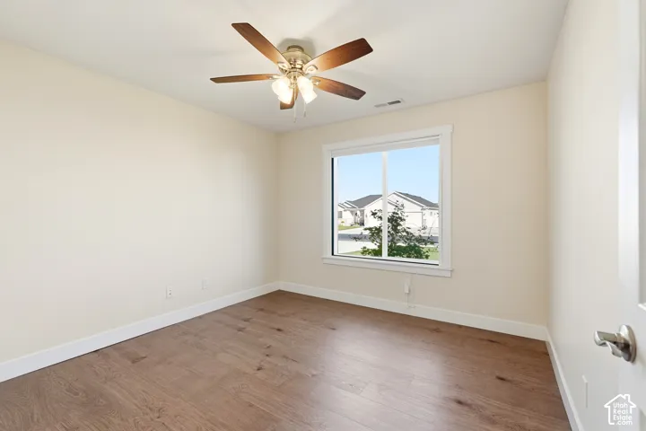 Wood-finish flooring, white trim, a ceiling fan with integrated lighting, and a window providing natural illumination