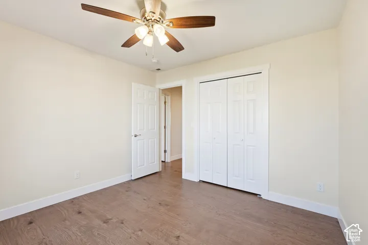 Wood-finish flooring, ceiling fan with integrated lighting, white paneled doors, and bi-fold closet doors