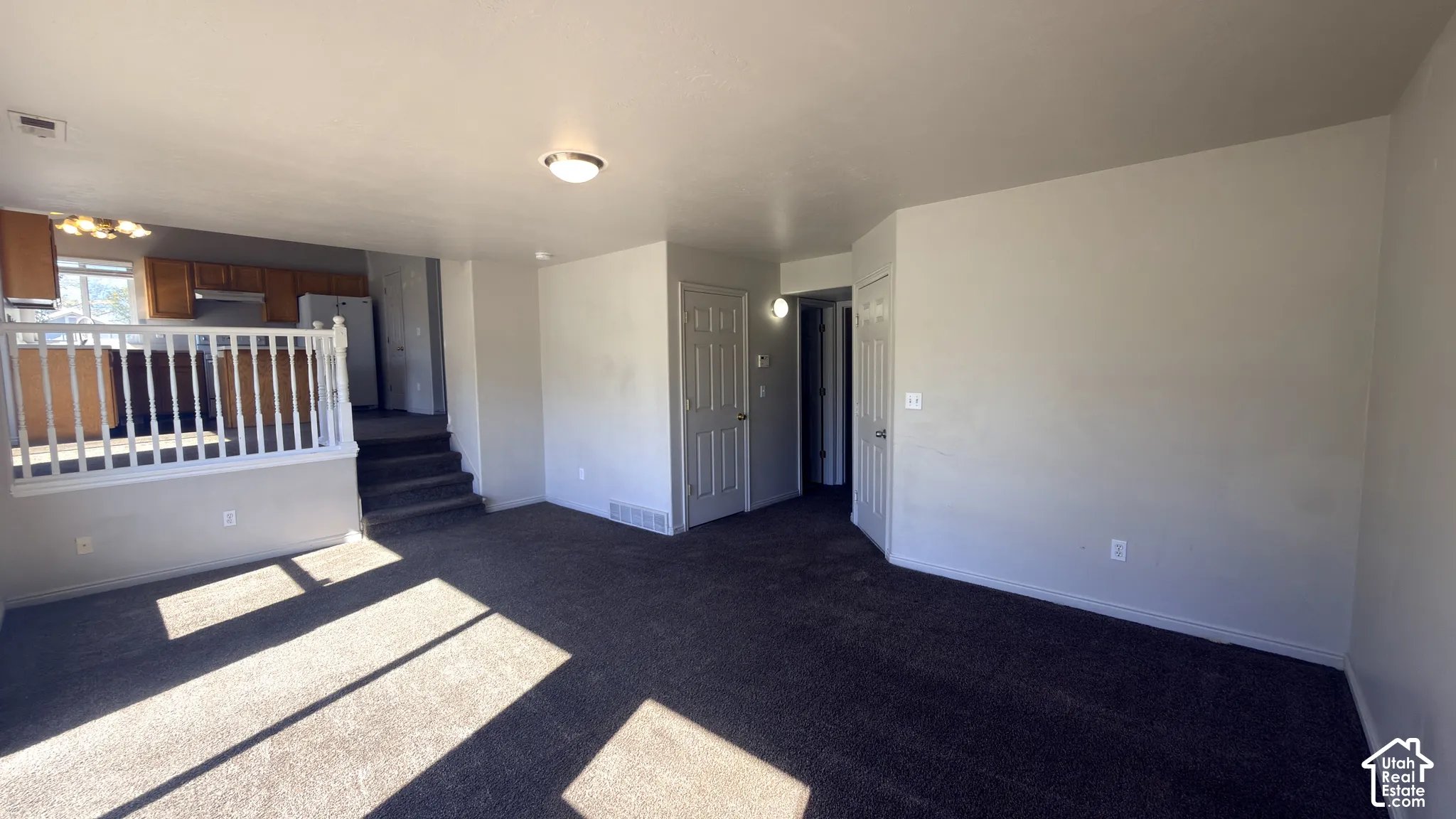 Carpeted living area with light gray walls and a built-in railing