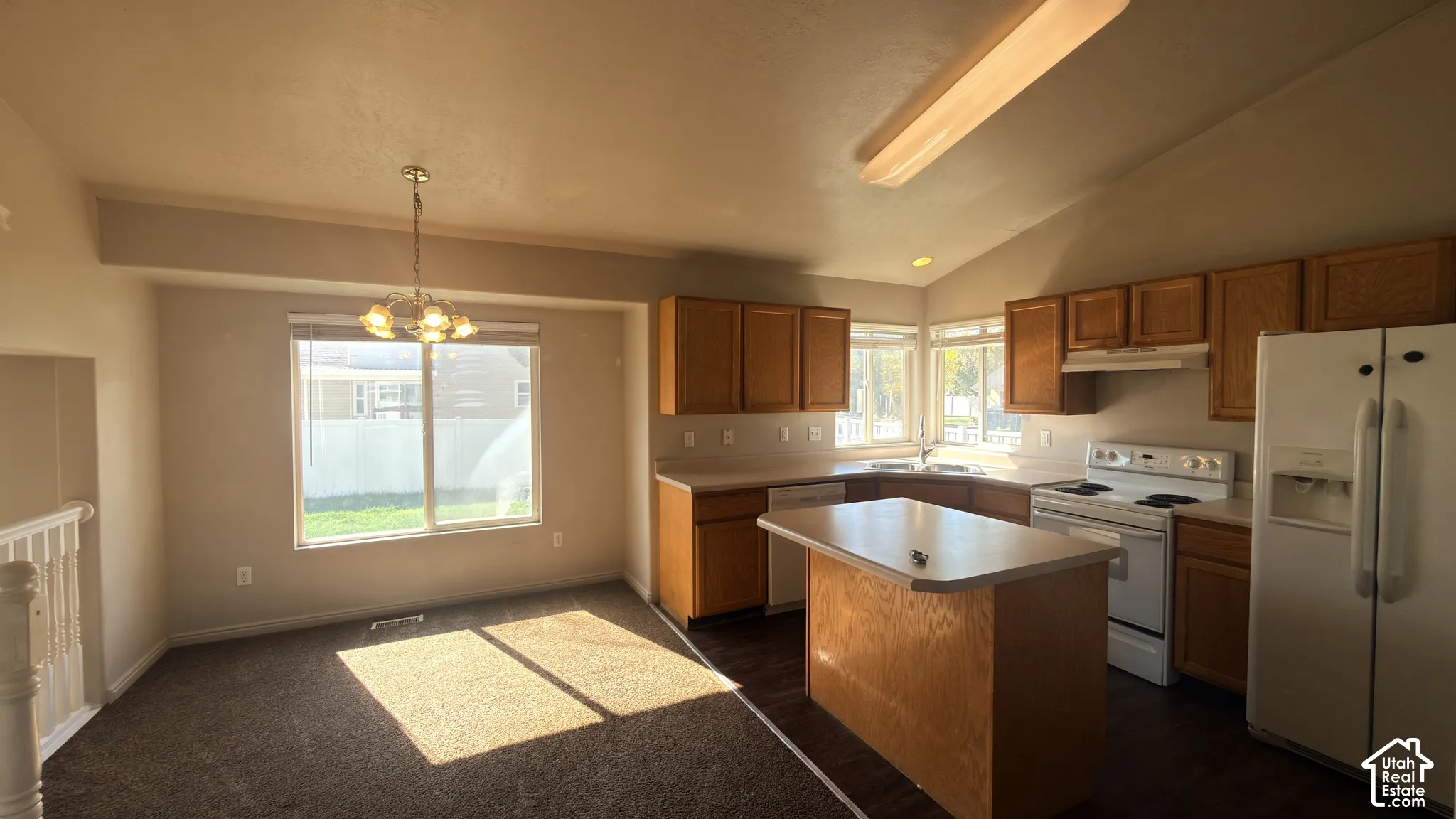 Kitchen and dining area featuring wood-finish cabinetry, white appliances, and a central island