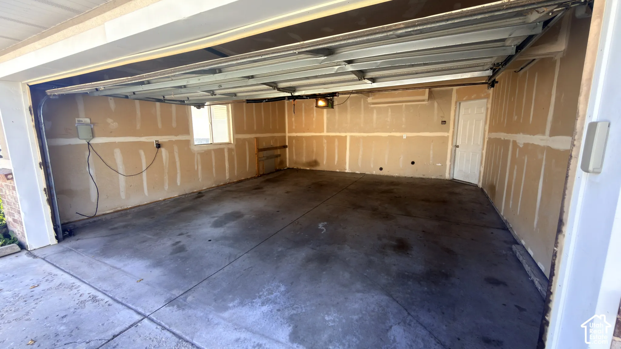 Attached garage with a concrete floor, exposed drywall, and a functional window