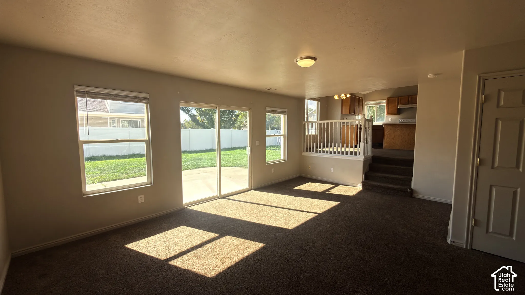 Sliding glass door leading to a concrete patio, a single-hung window, white interior railing, and wood-finish cabinetry