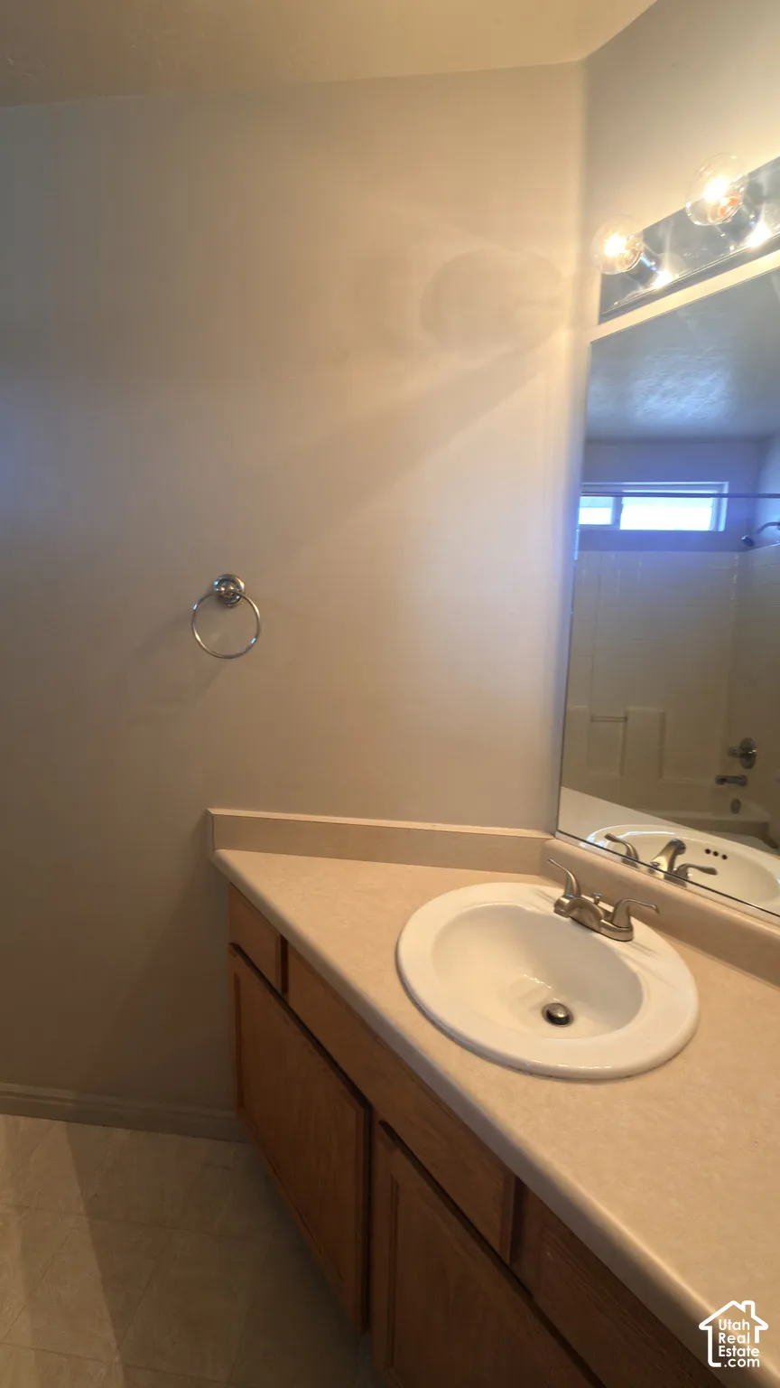 Vanity with an integrated sink and light-toned countertop, wood-finish cabinetry, and a wall-mounted mirror