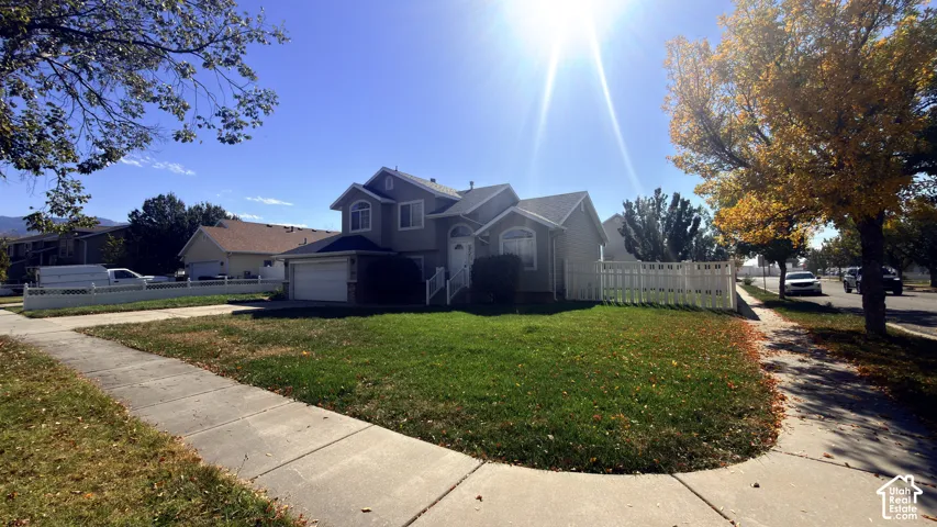 Two-story residence featuring a two-car garage, white picket fence, and mature trees