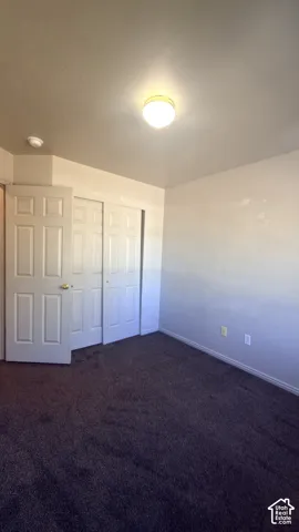 Recessed lighting, neutral wall paint, dark carpeting, and paneled closet doors