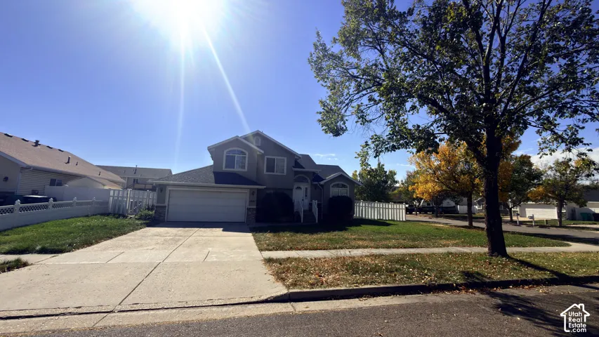 Two-story residence with a two-car garage, concrete driveway, and a white picket fence
