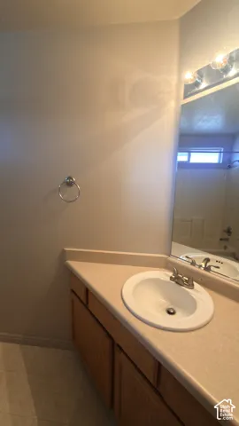 Vanity with an integrated sink and light-toned countertop, wood-finish cabinetry, and a wall-mounted mirror