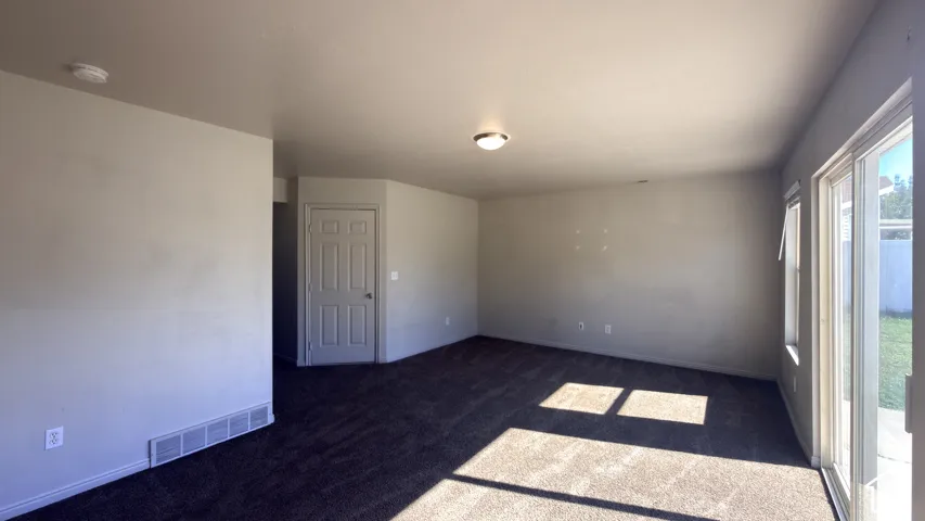 Carpeted flooring, neutral wall tones, recessed lighting, and a sliding glass door with an exterior concrete patio