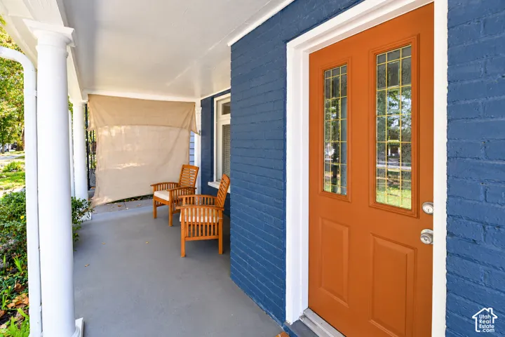 Covered front porch featuring a painted brick exterior, classic white columns, and a solid door with dual glass panels