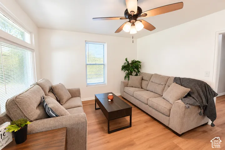 Wood-finish flooring, multi-pane windows, and a three-light ceiling fan with integrated cooling blades