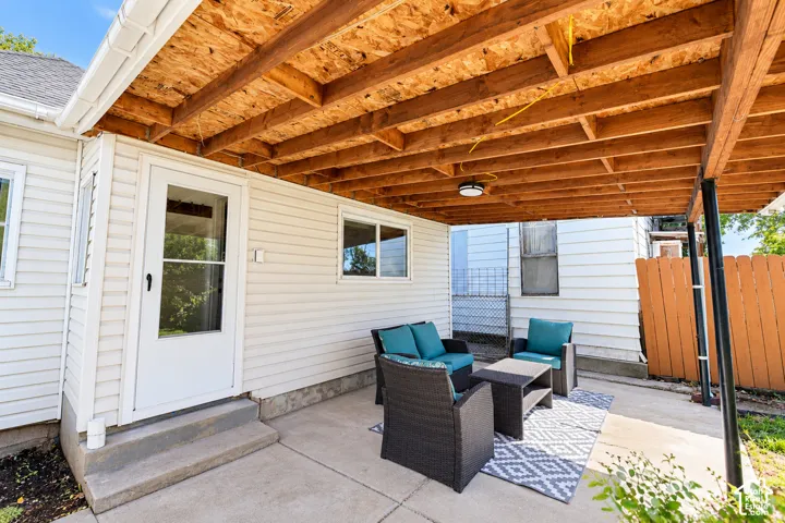 Covered concrete patio featuring exposed wood-beam ceiling structure and white vinyl siding