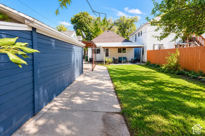 Backyard featuring a concrete patio, covered structure, wood-style horizontal siding on the garage, and a privacy fence
