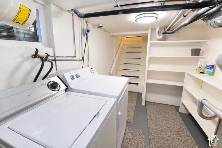Utility area featuring built-in open shelving, stairs with handrail, surface-mounted lighting, and a window