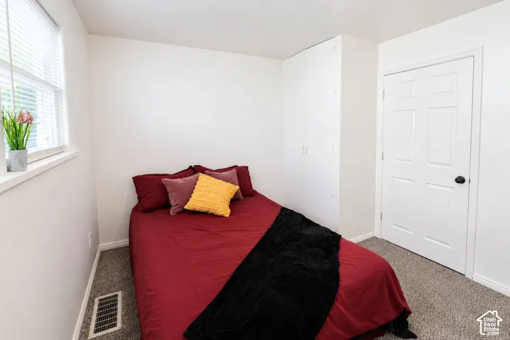 Room featuring carpeted flooring, a six-panel door, and floor-to-ceiling built-in cabinetry with white finish