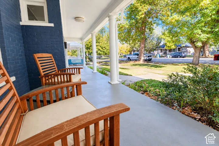 Covered front porch featuring white structural columns, painted masonry exterior, and smooth concrete flooring