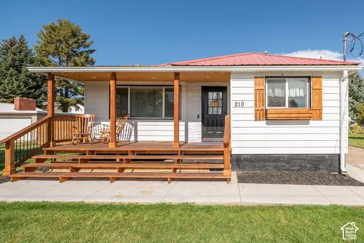 Exterior featuring a red metal roof, white siding, and a wooden porch with railings